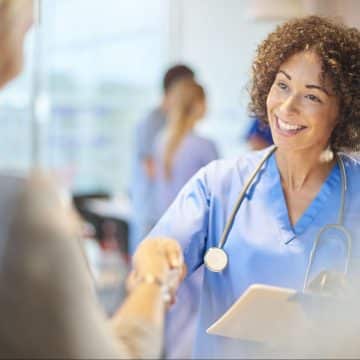 female doctor smiling and shaking hands with another person
