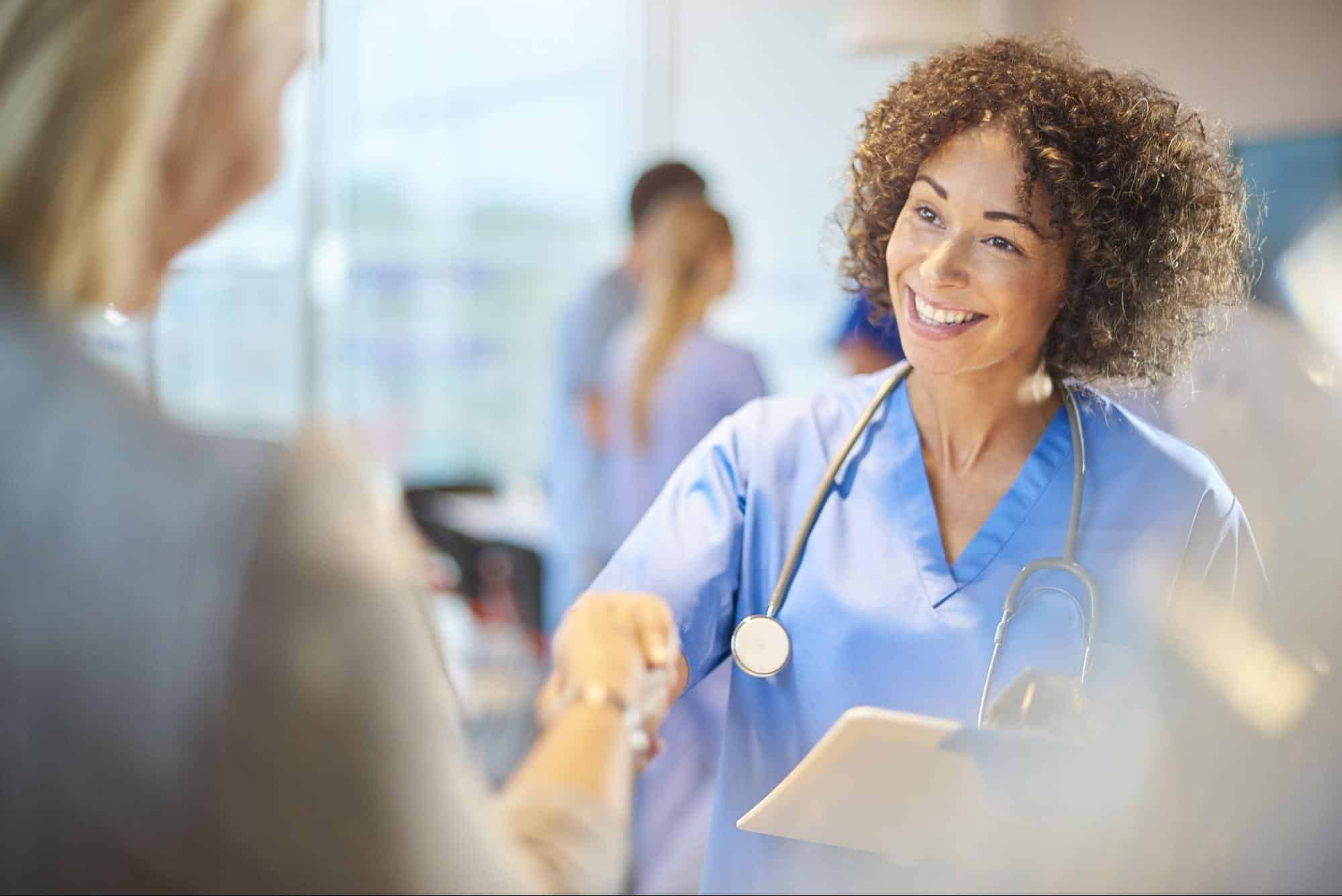 female doctor smiling and shaking hands with another person